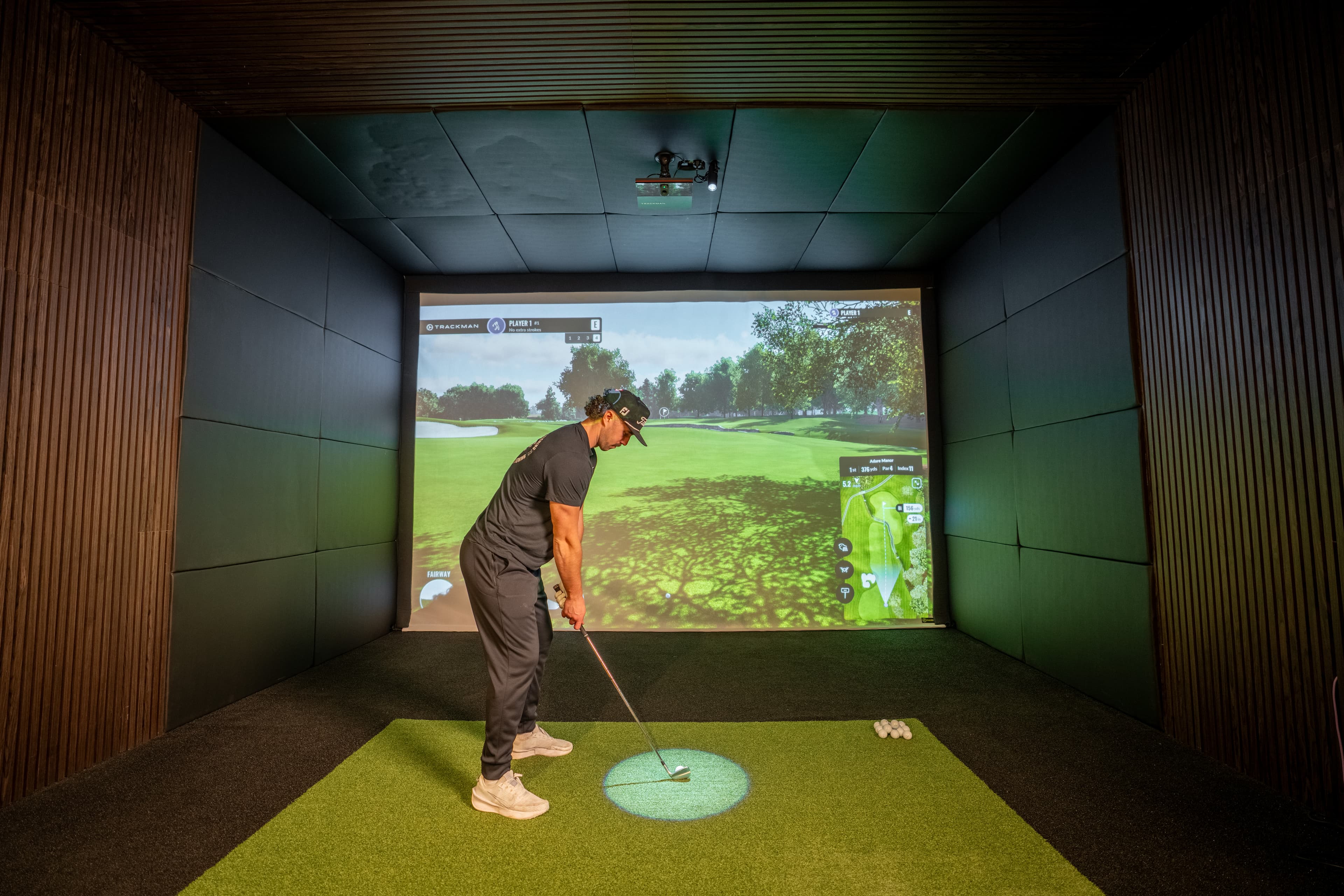 A golfer addressing the ball in the Studio 22 golf simulator
